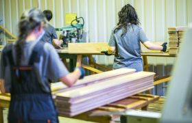 Tre kvinners lager innendørspanel i en trevarefabrikk