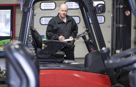 En mann står bak en truck i arbeidsklær