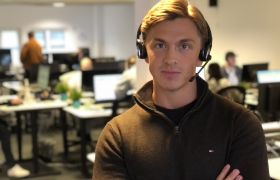 Telefonselger Kristoffer Bjørkamo står i lokalet han jobber med headsetet han bruker når han ringer på.